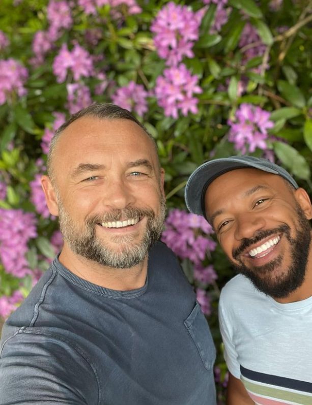 Paul White with Craig Rowe in front of flowers