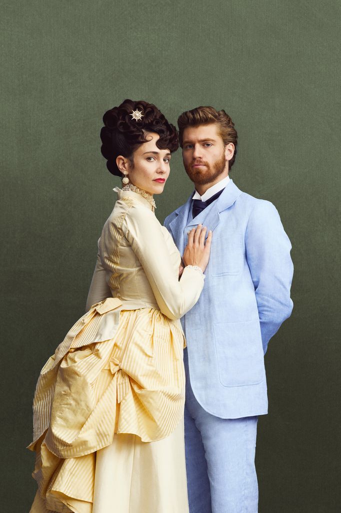 woman in yellow dress and man in blue suit against green background