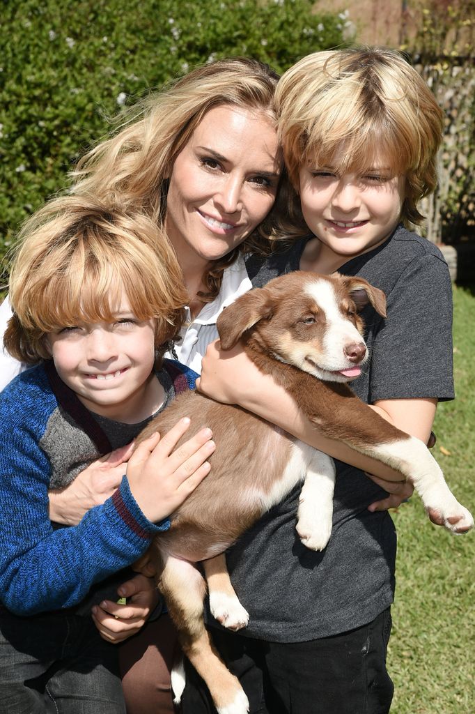 Brooke Mueller in white shirt posing with kids Max Sheen and Bob Sheen holding puppy in 2016
