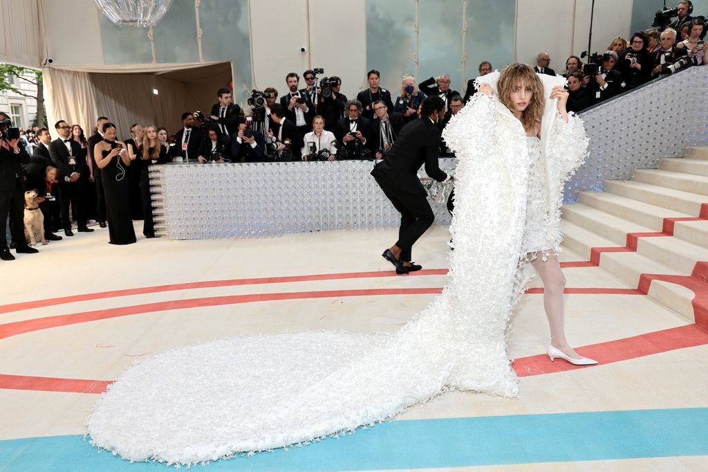 Maya Hawke est une vraie Carrie Bradshaw en robe de mariée « vintage » en satin et voile gonflé 6 Maya Hawke sur le tapis rouge en robe blanche et châle avec traîne