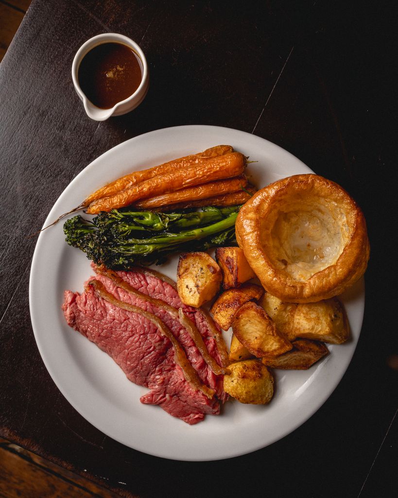 A roast dinner with beef, potatoes, Yorkshire pudding, tenderstem broccoli and carrots