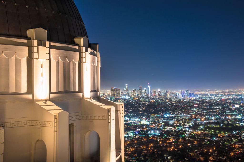 Griffith Observatory at night with the Los Angeles skyline in the distance.
