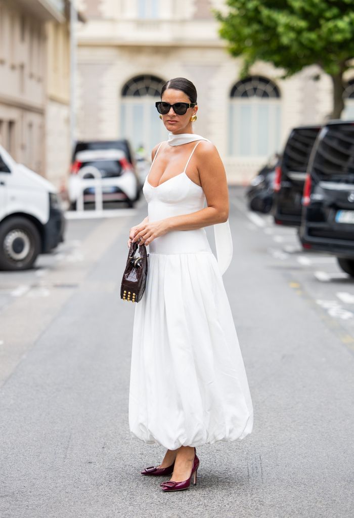 Gili Biegun wears white dress Shona Joy, burgundy heels / shoes Roger Vivier, brown bag Virag Kerenyi, sunglasses Saint Laurent, earings 
