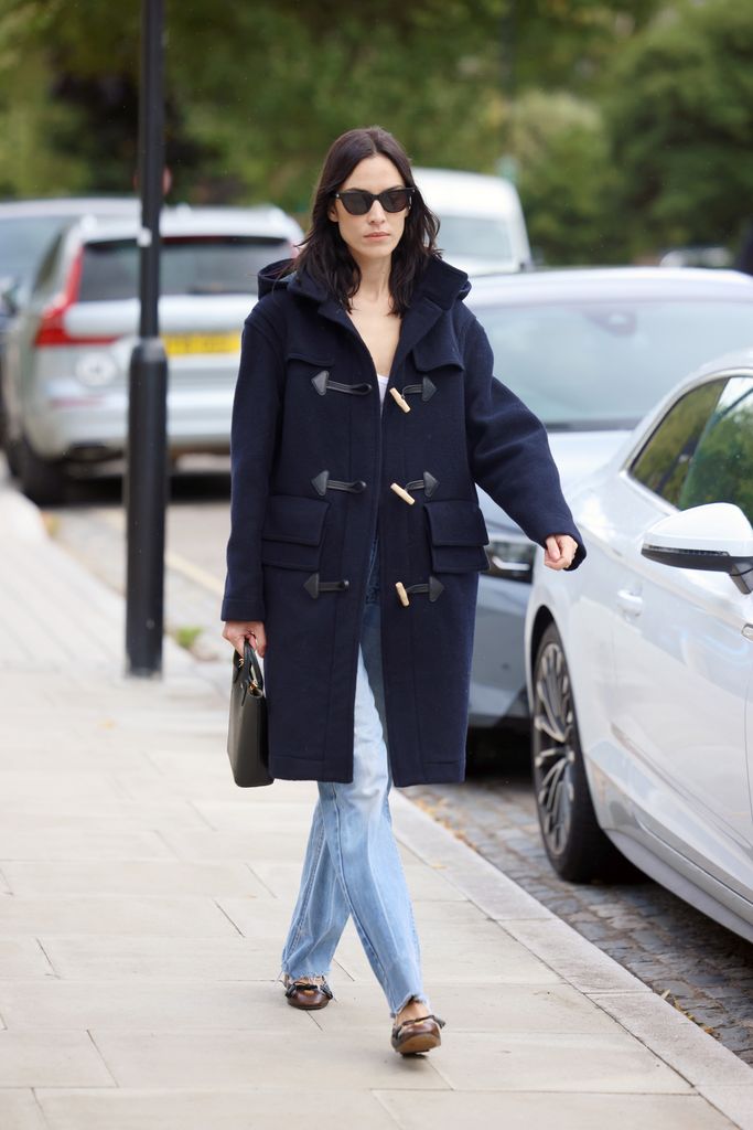 alexa chung wears blue jeans and a navy duffle coat while out in East London