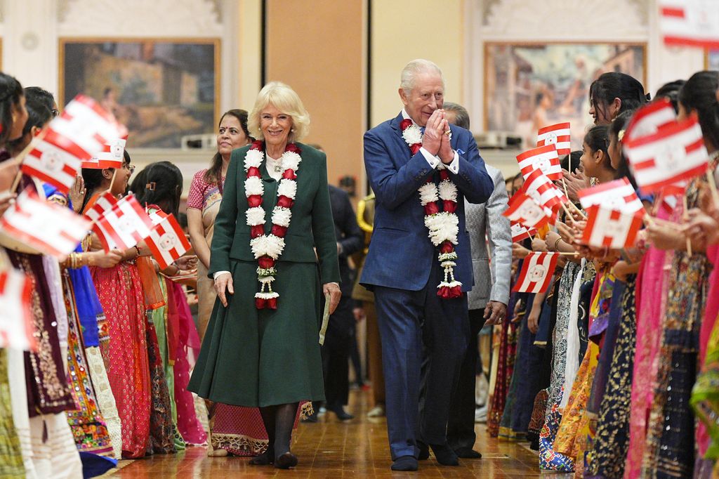 Britain's King Charles III (R) and Britain's Queen Camilla (L) are greeted by children as they arrive for a visit the BAPS Shri Swaminarayan Mandir, more popularly known as 'Neasden Temple', a traditional Hindu stone temple, to celebrate the temple's 30th anniversary in London on October 29, 2025.