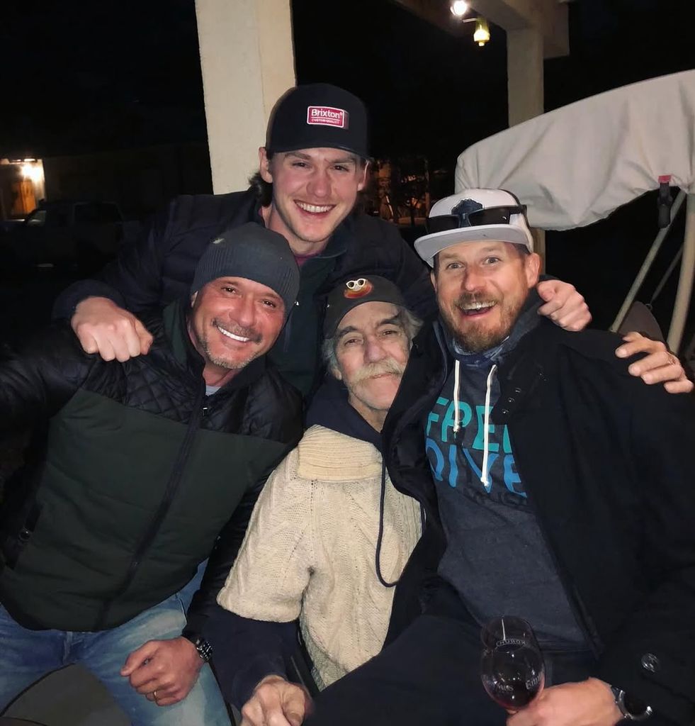 Tim McGraw in jacket and beanie posing outside with his brothers and late uncle