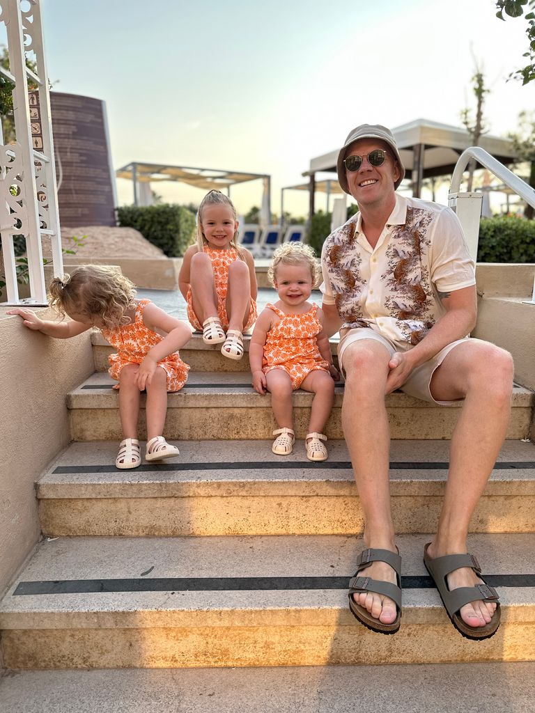 Dad Influencer Olly with his girls sitting on steps on holiday