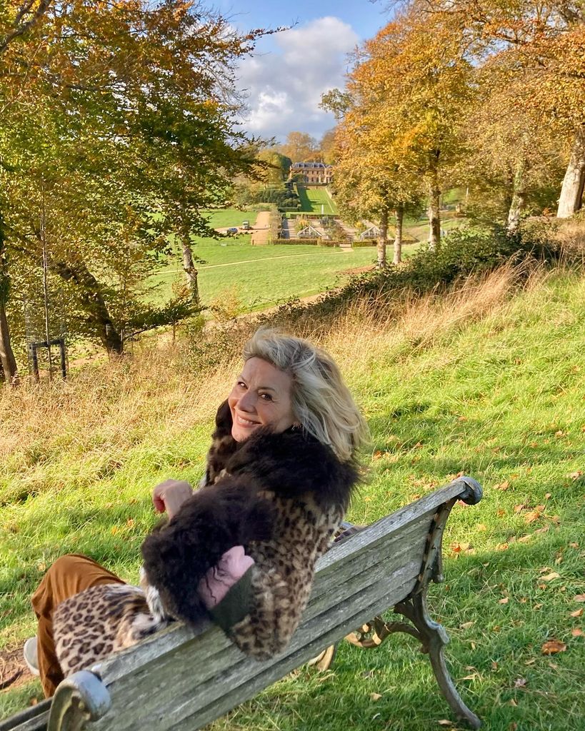 Glynis Barber sitting on a bench in the sun