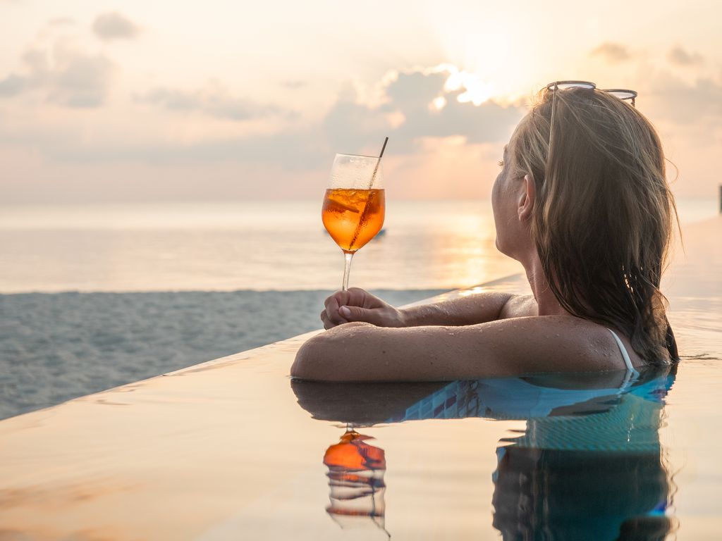 Woman on tropical beach relaxing with cocktail and enjoying sunse