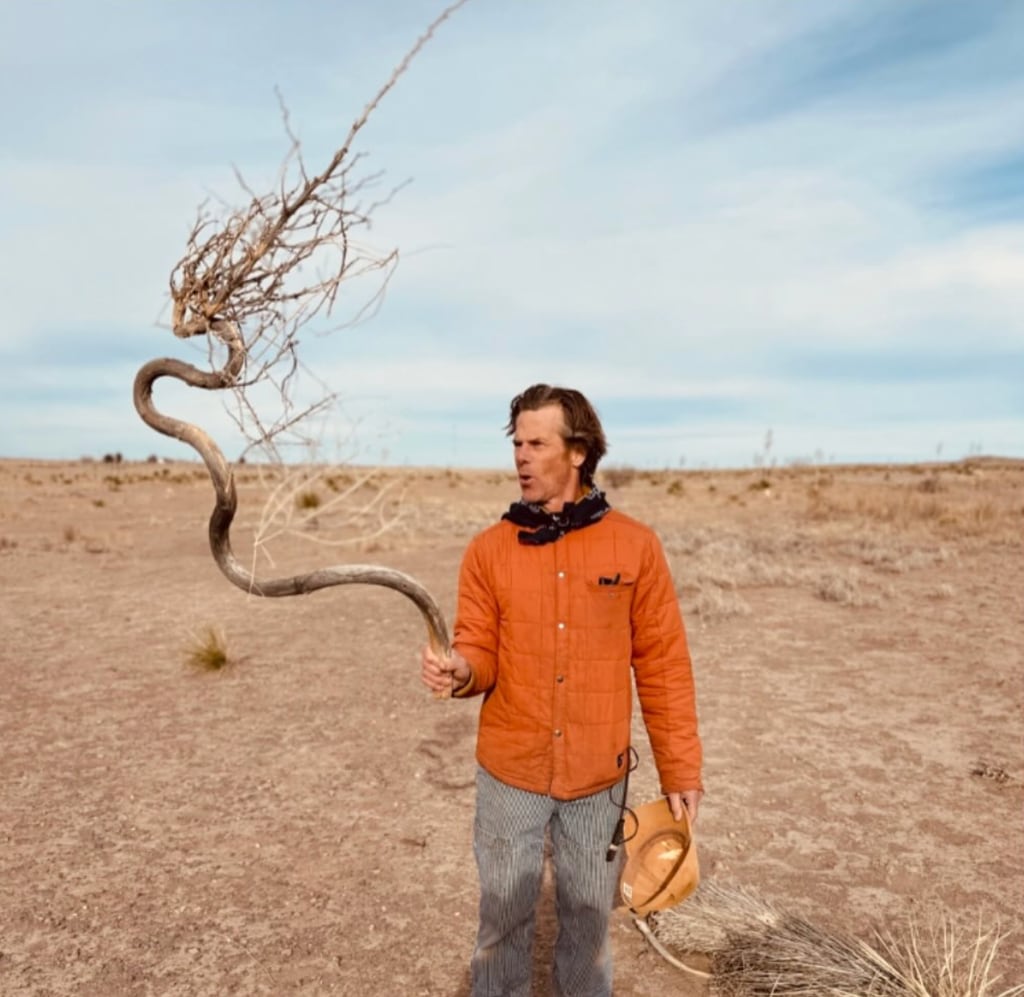 Photo shared by Julia Roberts on Instagram of her husband Danny Moder with a tree branch standing in an arid field