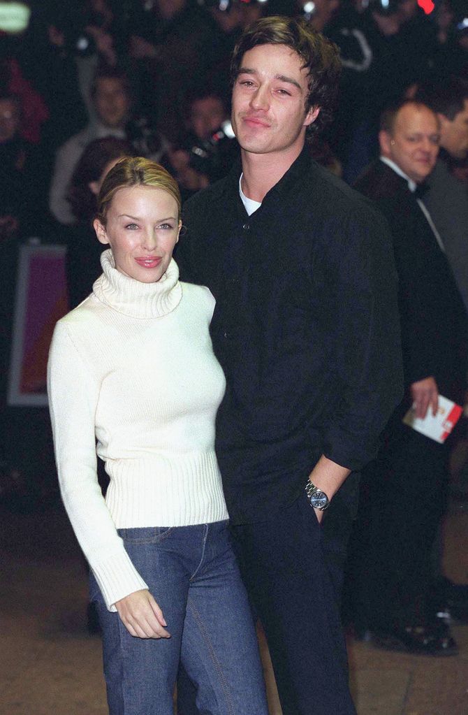 Kylie Minogue in white jumper and jeans with James Gooding in a black outfit