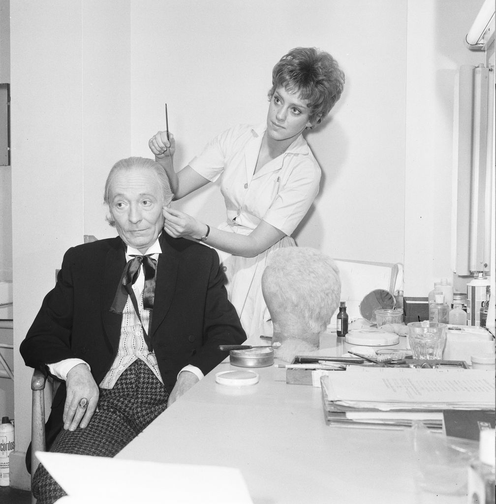Actor William Hartnell - the first Doctor - pictured in dressing room as make up artist Sonia Markham applies the finishing touches to his face makeup & wig at BBC Television Centre, Wood Lane 9th January 1966, This saturday (15th January) will see the airing if the 100th Dr Who Episode. (Photo by Arthur Sidey/Mirrorpix/Getty Images)