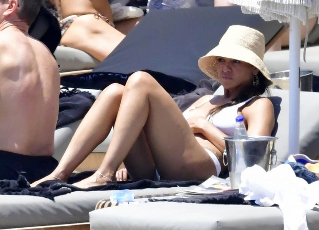 Luciana Barroso lounges on a sun lounger in a straw hat and white bikini 