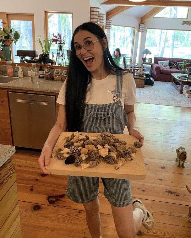 Demi moore holding board of mushrooms in kitchen