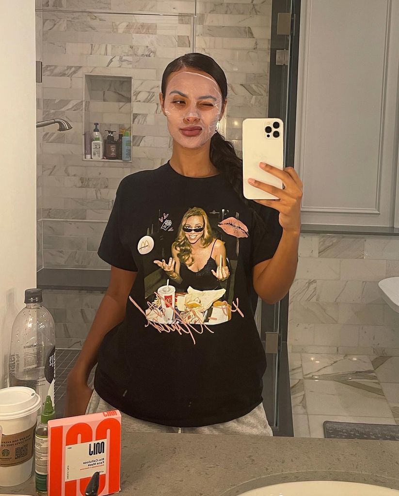 Maya Jama wears a face mask and poses in the mirror of her bathroom