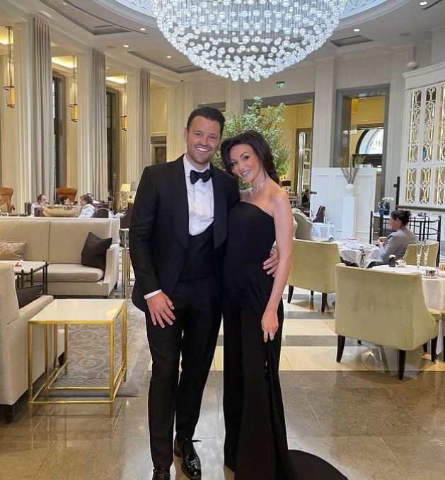 Un letrero negro con la mano con la mano alrededor de Michelle Keegan con vestido negro