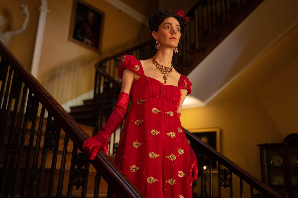 A woman in a red dress walks down the stairs