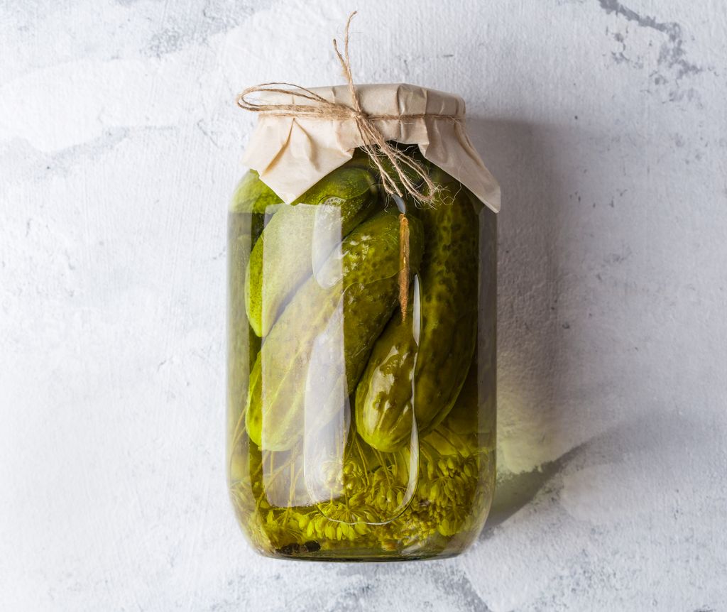 Fermentation cucumbers in glass jar. Pickling and fermentation cucumber in glass jar with dill and garlic on grey table. Copy space.