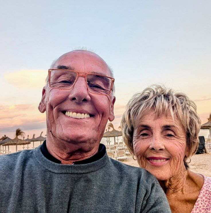 An elderly couple smiling while on the beach