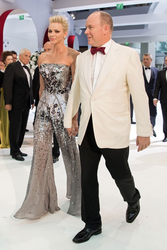 Princess Charlene n silver jumpsuit and Prince Albert in white suit jacket 