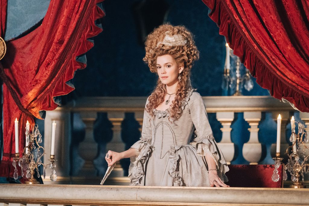 woman in period clothing standing on balcony