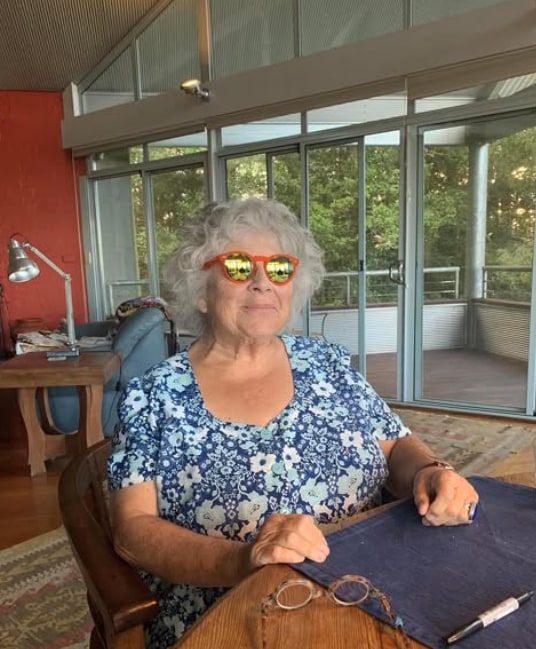 woman at wooden table with sunglasses on