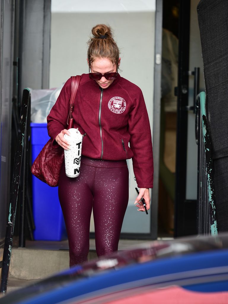 Jennifer wears maroon leggings with her high school jacket