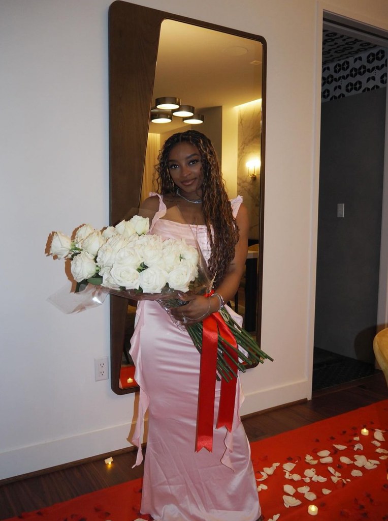 Photo shared by Simone Biles on Instagram Valentine's day of herself in a pink silk dress holding white roses from her husband Jonathan Owens