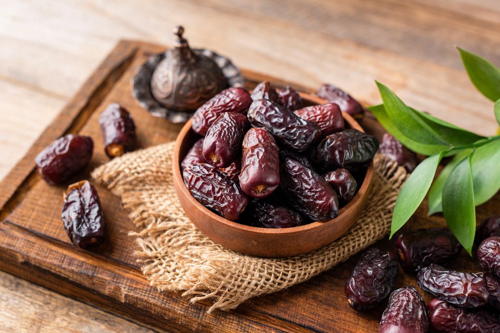 Dried date fruits in wooden bowl, tasty medjool dates. Islamic arabic food, vegan sugar