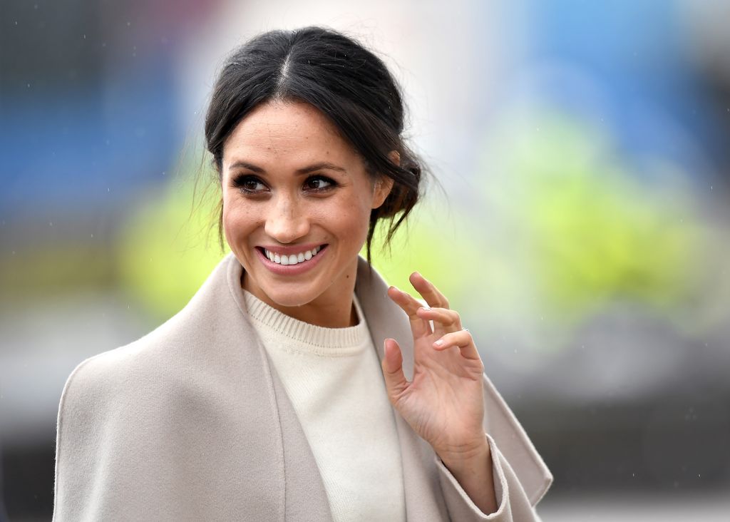 woman waving in cream jumper