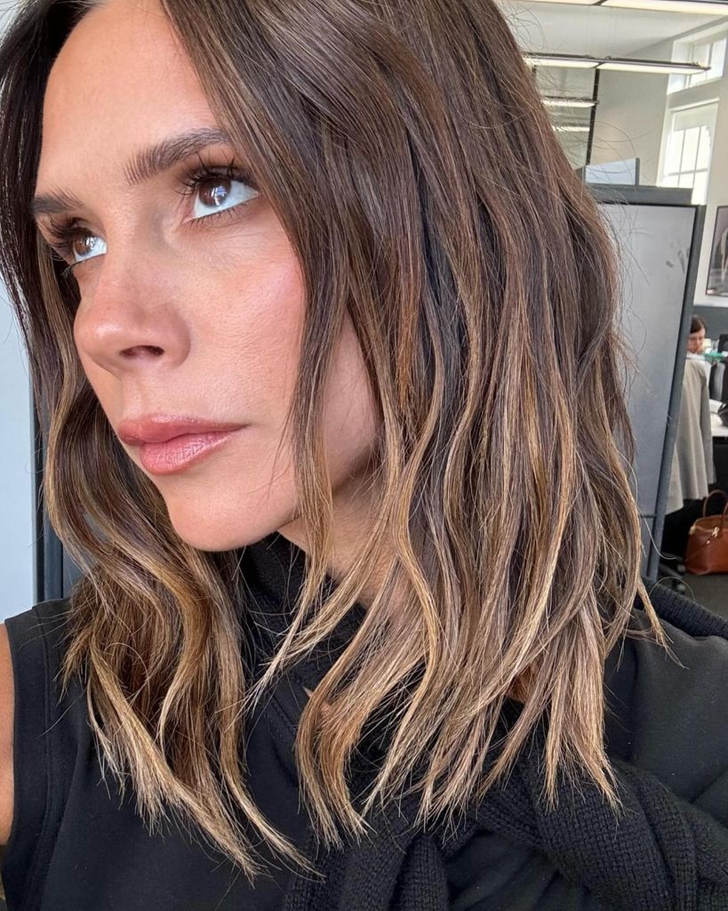 Victoria Beckham looking up off camera with her hair lightly tousled 