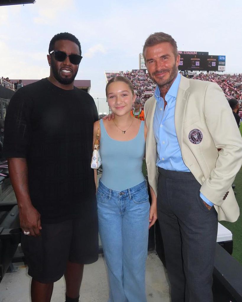 Harper Beckham in blue bodysuit and baggy jeans posing with P Diddy and father David Beckham
