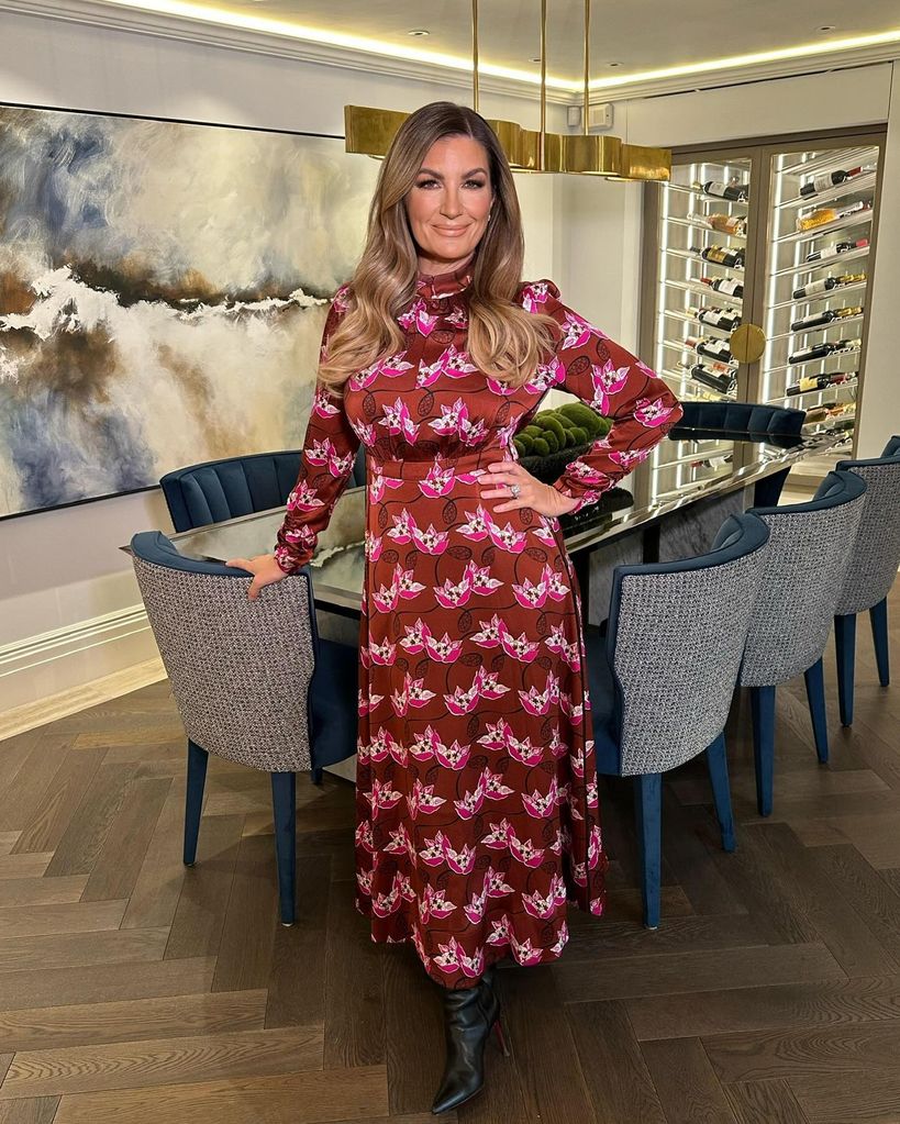 Karren Brady wears a red dress and stands in her dining room 