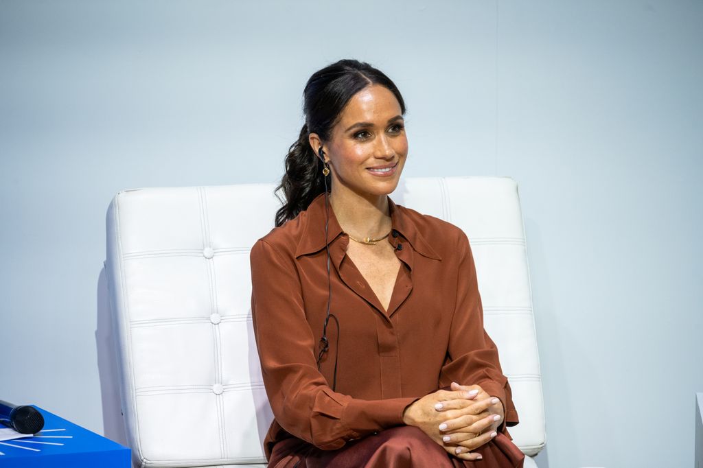 Meghan Markle wearing brown shirt and smiling