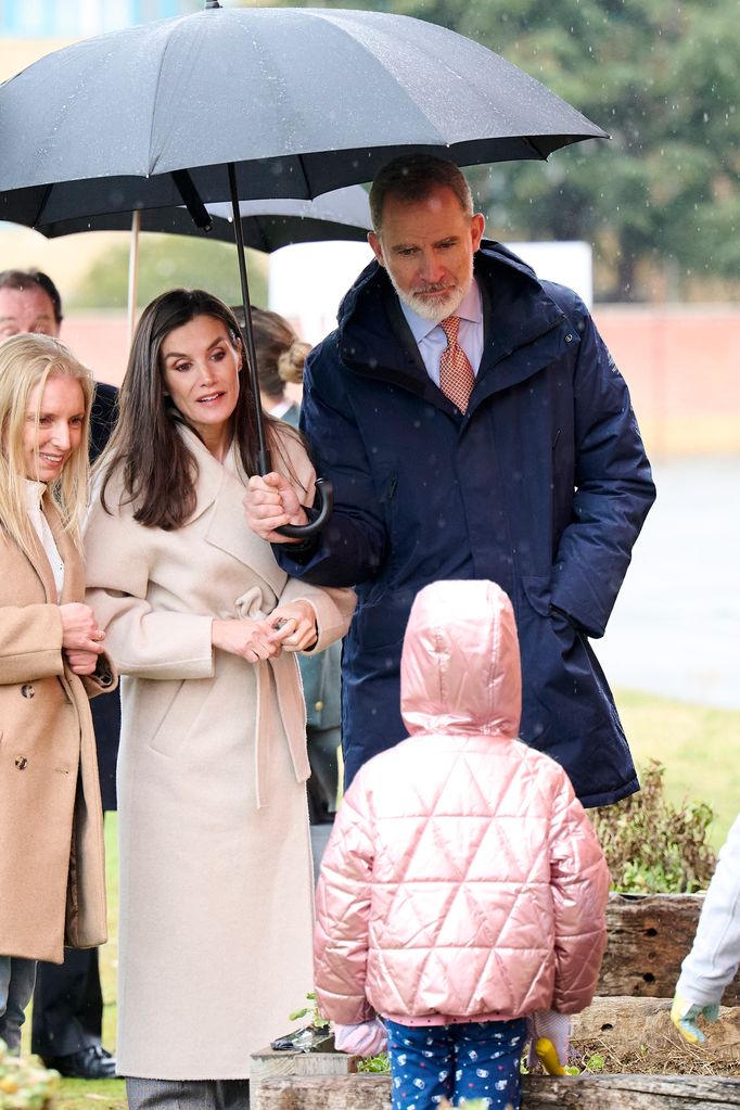 Queen Letizia in a cream coat with Felipe under an umbrella