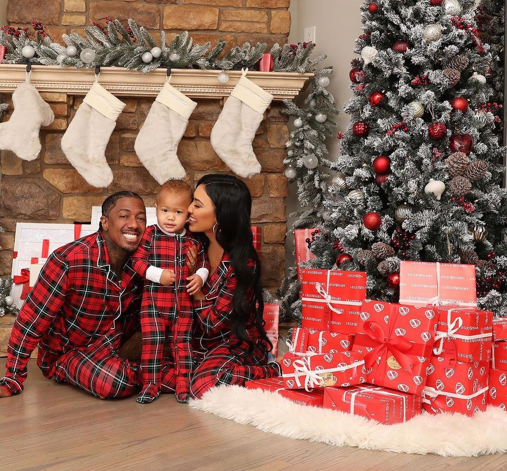 Nick Cannon and Bre Tiesi kss their son Legendary next to a Christmas tree