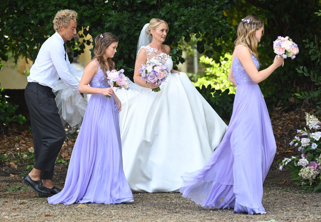 Anne-Marie Corbett holding up her wedding dress and walking with her two daughters