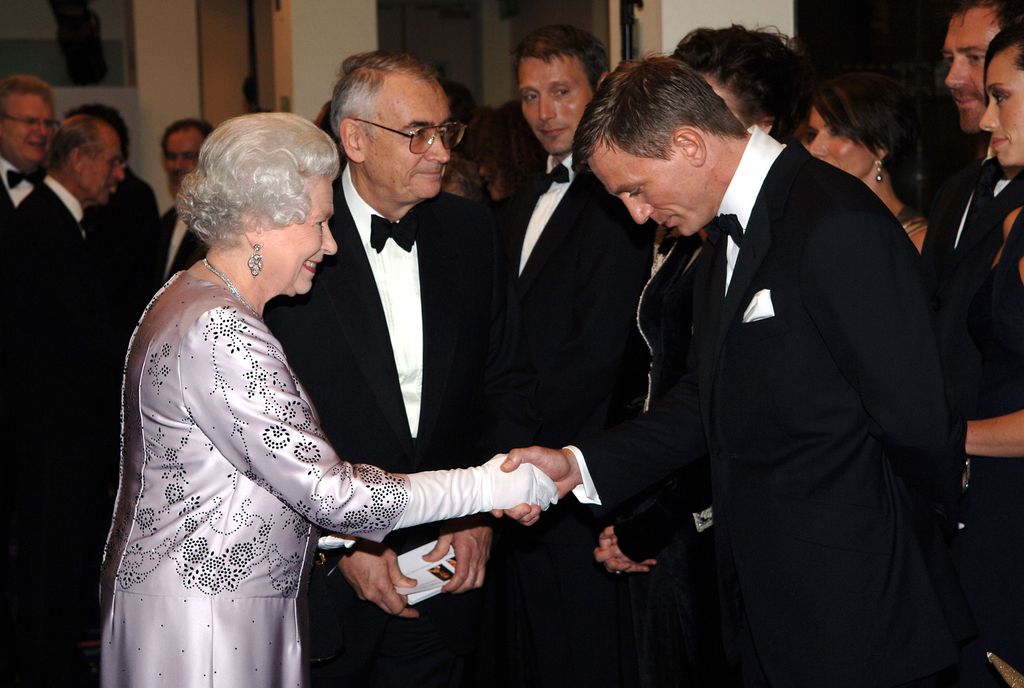 The Queen wearing a silver gown and white gloves whilst shaking hands with Daniel Craig at the Royal Premiere for the 21st Bond film 'Casino Royale' in 2006