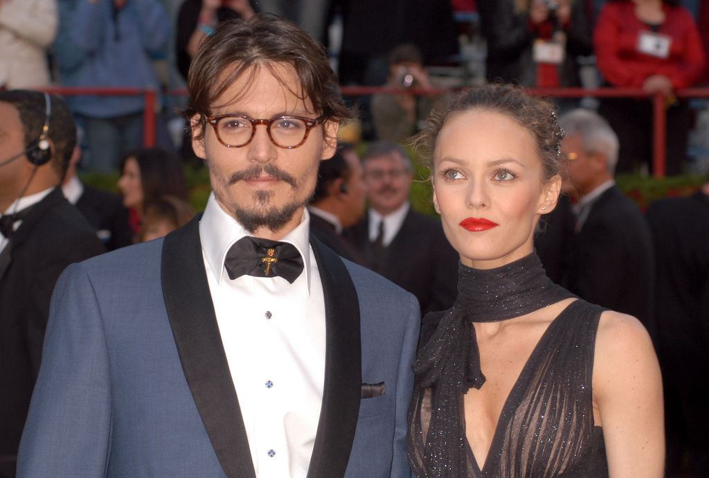 Johnny Depp wears a blue suit and Vanessa Paradis wears a sheer glittery black dress at the 77th Annual Academy Awards