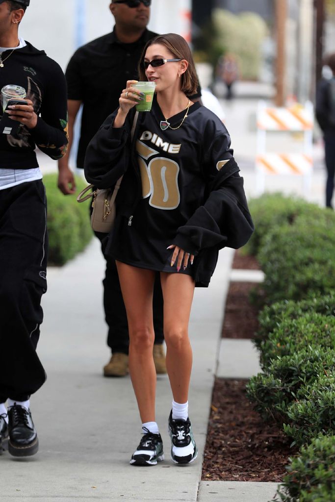 hailey bieber in some sneakers and a beige leather bag
