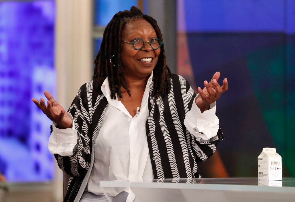 Whoopi Goldberg smiling and raising her arms on The View