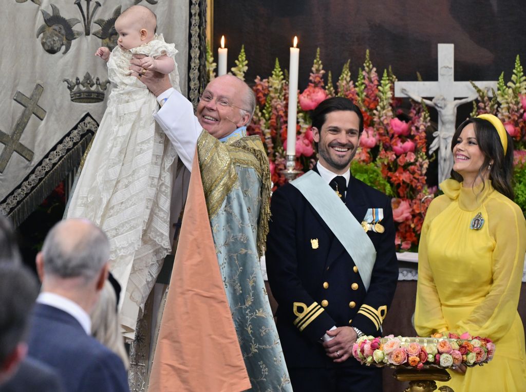 The chief priest, Bishop Johan Dalman, holds up Princess Ines after he baptizes her