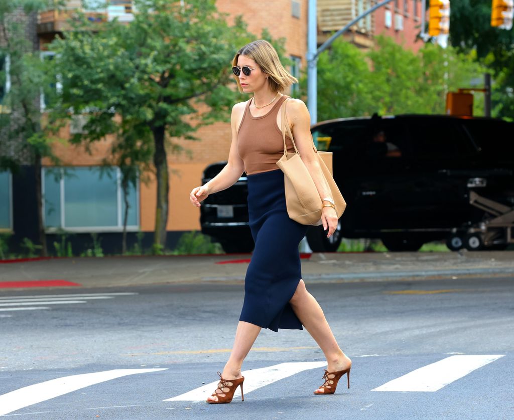 Jessica Biel walking in tan top and navy skirt 