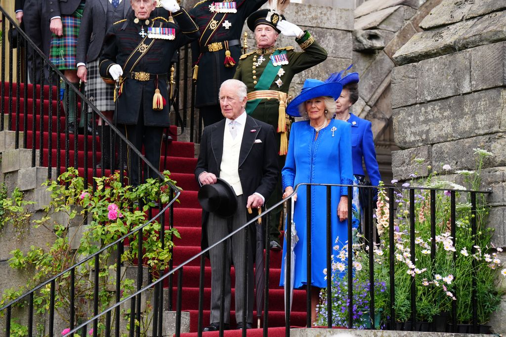 King Charles III and Queen Camilla, followed by Princess Anne, Princess Royal, stand on the steps as the national anthem is played as they arrive for the Sovereign's Garden Party at the Palace of Holyroodhouse