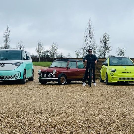 Simon Cowell posing with his fleet of electric cars on his driveway