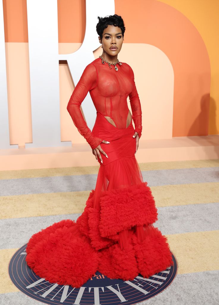 Teyana Taylor at the Oscars afterparty wearing bright red Laquan Smith, a sheer long sleeve mesh top with cut out detailing just above the hips and a full tiered tulle skirt