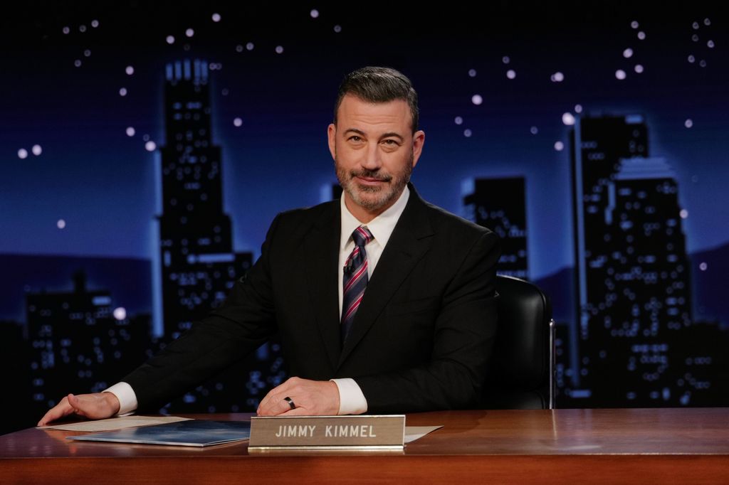 Jimmy Kimmel in black blazer, stripe tie, and white shirt in studio