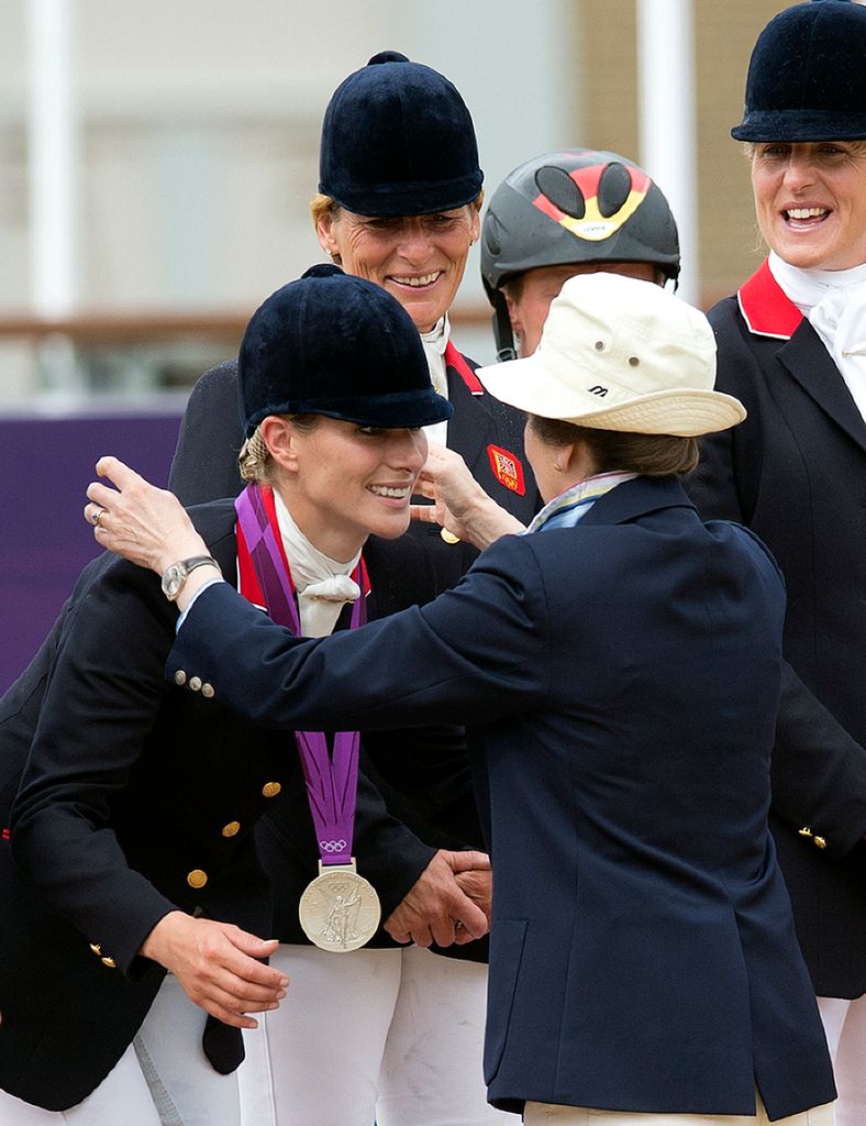 Zara sorri ao receber sua medalha de prata de sua mãe, a princesa Anne