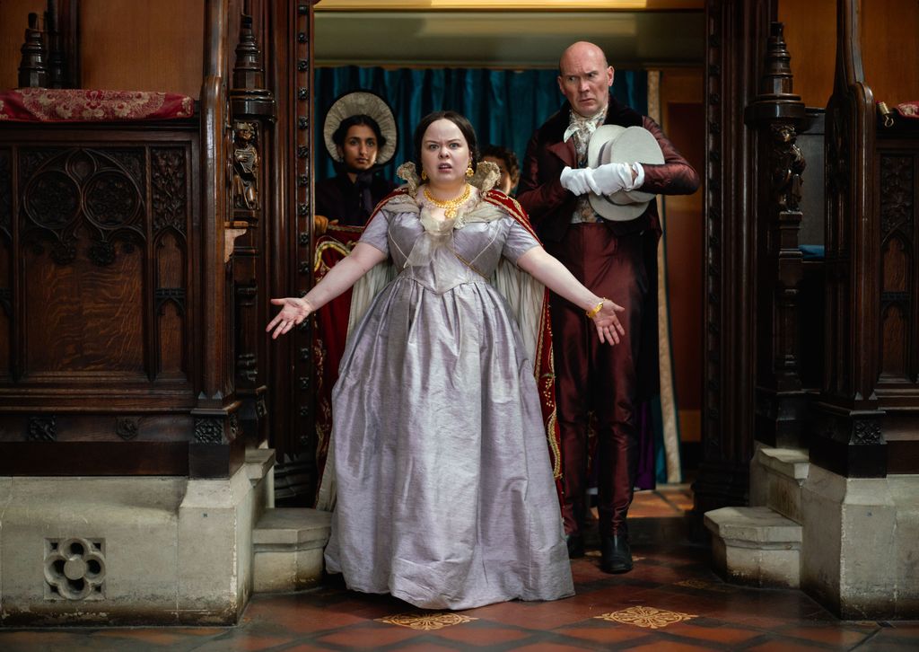 Nicola Coughlan wearing a purple gown as Queen Victoria