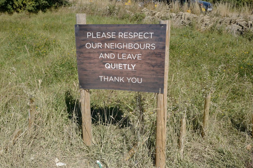 A signpost saying 'please resepct our neighbours and leave quietly thank you' 